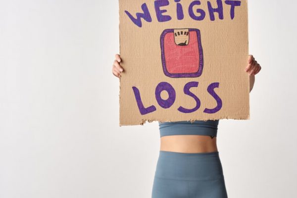 Person holding 'weight loss' sign for fitness motivation and health goals.