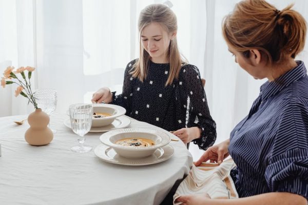 A serene scene of a mother and daughter dining together in a bright, cozy setting.