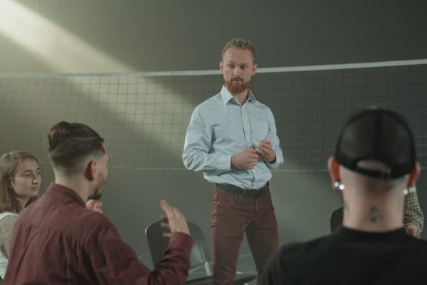 Four people engaged in a group discussion inside a room with a net background.